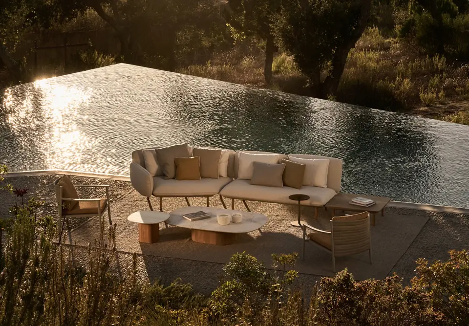 Tribù Senja modular sofa with an integrated teak side surface beside an infinity pool