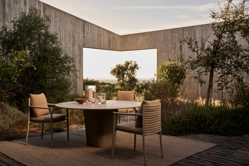 Tribù Tao round dining table on a concrete pedestal with rope-backed chairs on a walled garden terrace