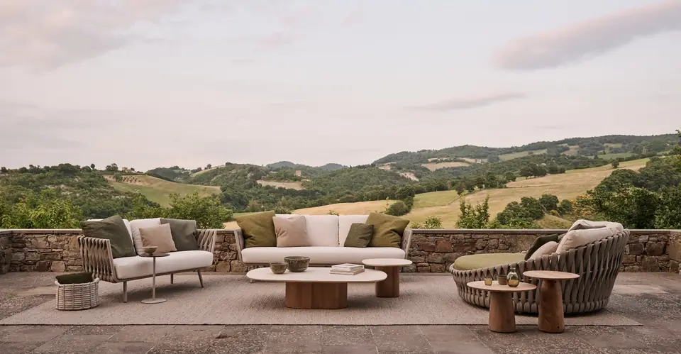 Tribù Tosca sofa, lounge chair and round braided daybed on a stone terrace above a valley