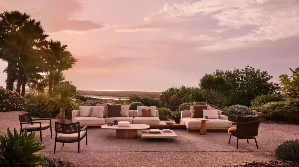 Tribù Vis à Vis modular sofa and daybed on teak bases with travertine low tables at sunset
